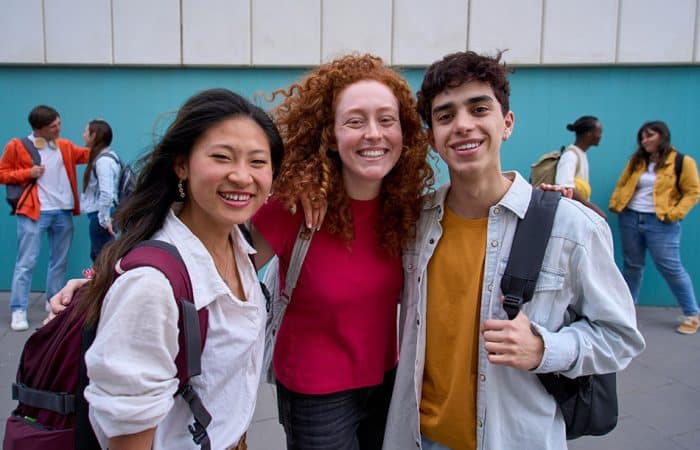 Three young adults standing on a college campus